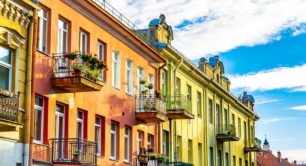 Traditionelles litauisches Haus in Kaunas mit steilem roten Ziegeldach, weiß gerahmten Fenstern und einem angelegten Balkon. Das rustikale Zuhause bietet eine charmante Wohnsituation in einem der ruhigen Viertel von Kaunas. Ein perfektes Beispiel für baltische Architektur und urbanes Leben.
