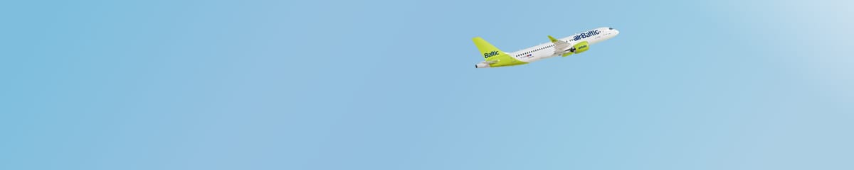 AirBaltic Airbus A220-300 w zielono-białym malowaniu lecący przez czyste, błękitne niebo.