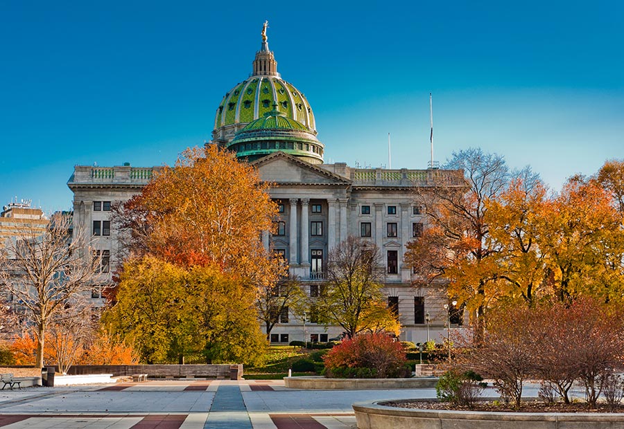 Pennsylvania State Capitol building framed by colorful autumn trees in Harrisburg.
