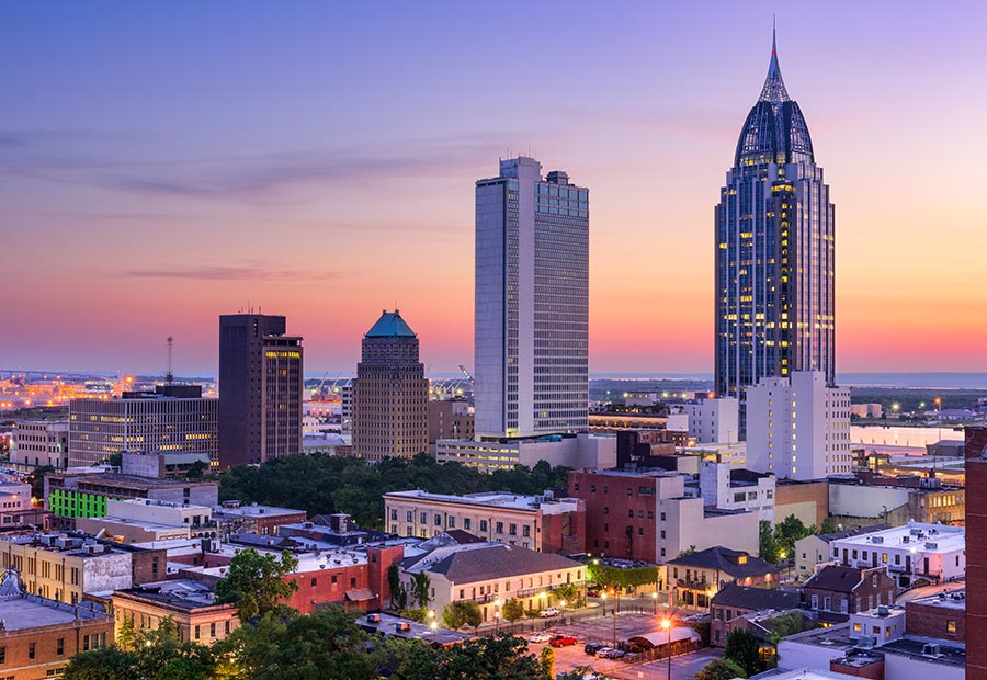 Downtown Mobile skyline at sunset with modern high-rise buildings.