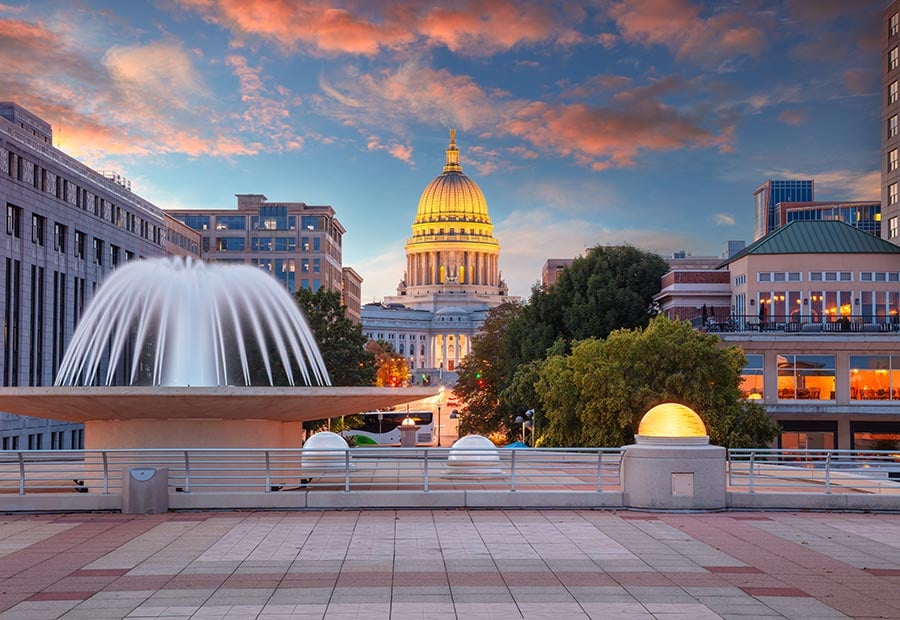 Wisconsin State Capitol building illuminated at sunset in downtown Madison.