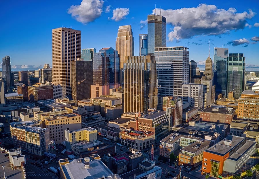 Downtown Minneapolis skyline with modern skyscrapers under a blue sky.