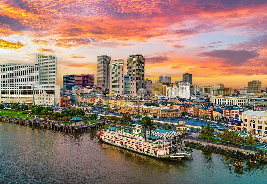 New Orleans skyline and Mississippi River waterfront at sunset.