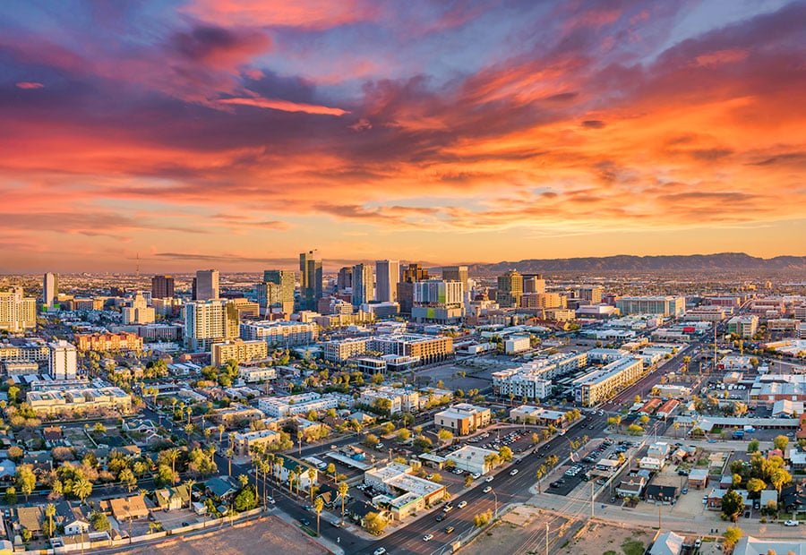 Downtown Phoenix skyline at sunset with desert mountains in the distance.