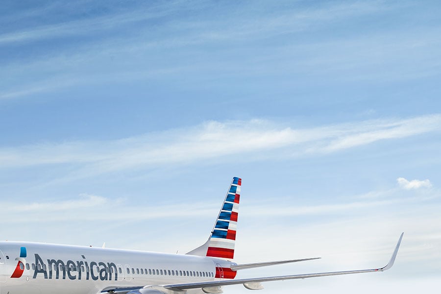 American Airlines aircraft with tail and wing visible against a partly cloudy sky.
