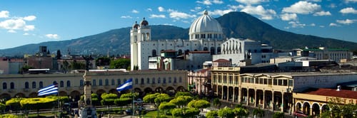 Vista panorรกmica del centro histรณrico de San Salvador con la Catedral Metropolitana y el volcรกn de San Salvador al fondo. Encuentra los mejores vuelos a Ciudad de Guatemala con tarifas flexibles y opciones de viaje adaptadas a tus necesidades.