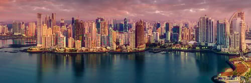 Vista panorรกmica del skyline de Ciudad de Panamรก al atardecer, con rascacielos reflejรกndose en la bahรญa. Reserva vuelos a Panamรก y descubre su vibrante vida urbana, su centro financiero y el famoso Canal de Panamรก.