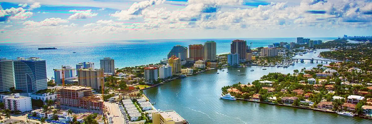 vista aรฉrea de Fort Lauderdale, Florida, con sus famosos canales, modernos rascacielos y el ocรฉano Atlรกntico de fondo. Reserva vuelos a Fort Lauderdale y disfruta de sus playas, compras y vibrante vida nocturna en la 'Venecia de Amรฉrica'