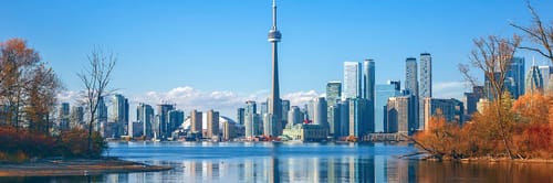 Vista panorรกmica de Toronto, Canadรก, con la icรณnica Torre CN y el lago Ontario de fondo. Encuentra vuelos a Toronto y descubre su vibrante cultura, rascacielos modernos y diversidad gastronรณmica.