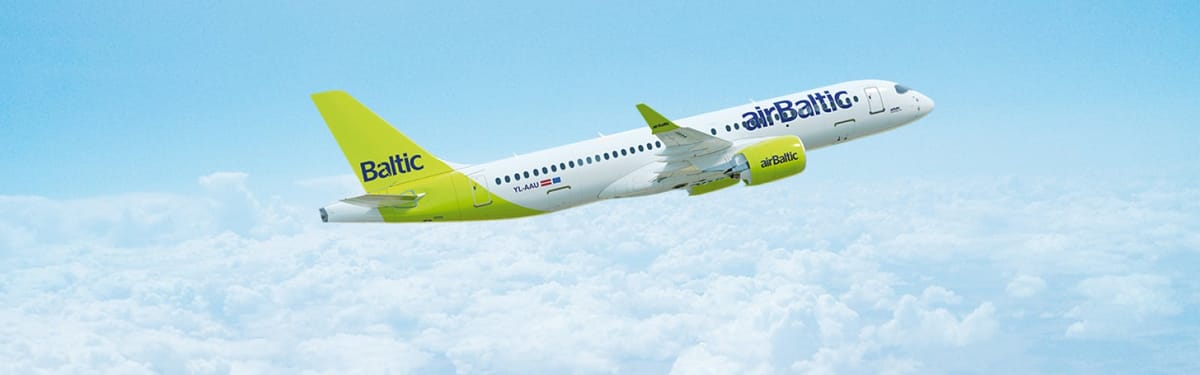 airBaltic Airbus A220-300 in green and white livery flying through a clear blue sky