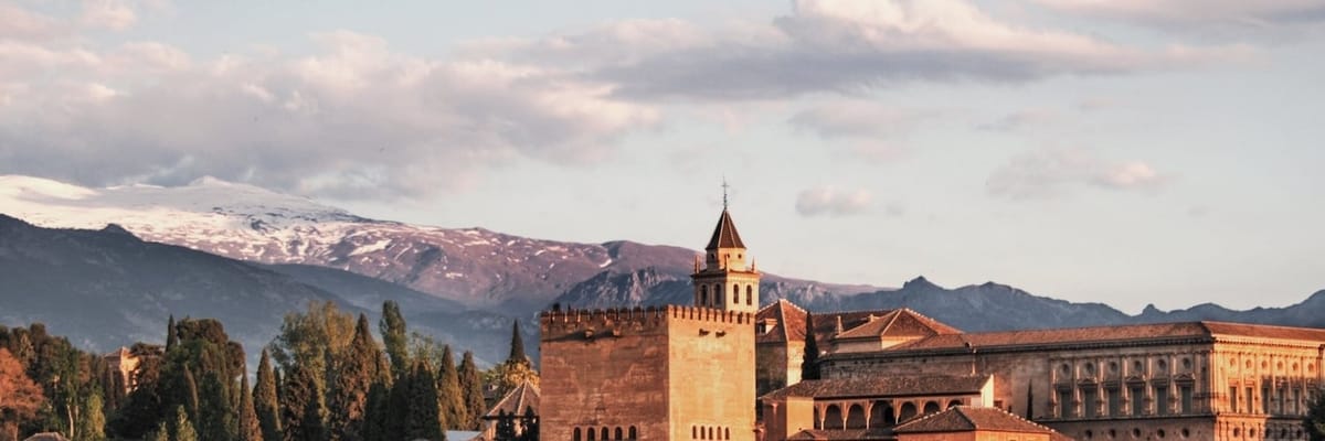 Alhambra palace complex in Granada, Spain with the snow-capped Sierra Nevada mountains in the background.