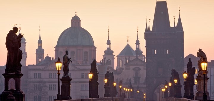 View of Charles Bridge in Prague with the Vltava River and city skyline.