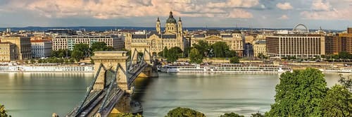 A panoramic view of Budapest, Hungary, featuring the Széchenyi Chain Bridge spanning the Danube River.