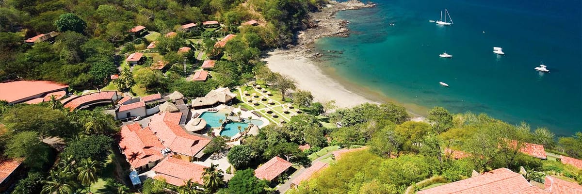 Aerial view of Secrets Papagayo and gold sand beach in an ocean cove in Liberia, Cost Rica