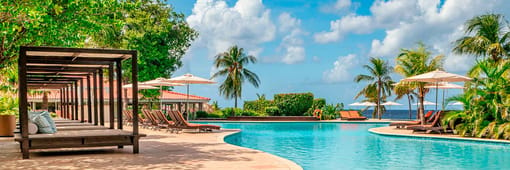 Dreams Curacao Outdoor infinity pool with portable reclining chairs and a separate covered lounging area