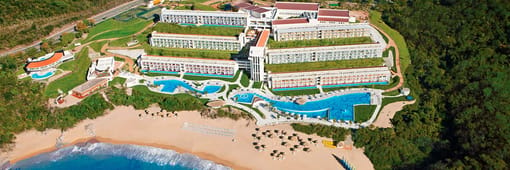 Distant oceanfront aerial view of resort and pools at Secrets Huatulco Resort & Spa