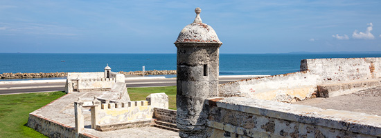 Murallas de piedra, garita colonial y vista al mar Caribe desde el Baluarte de Santa Catalina en Cartagena.