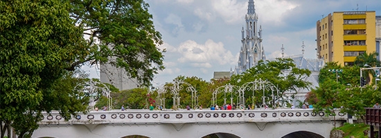 Riverside promenade, bridge, trees, and city views at Bulevar del Río in Cali.
