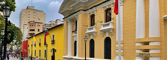 Edificios coloniales de colores y fachada institucional en una calle del casco histórico de Caracas, Venezuela.