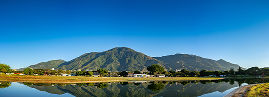 Lago sereno con reflejo de la montaña y paisaje verde en el Parque del Este de Caracas, Venezuela.