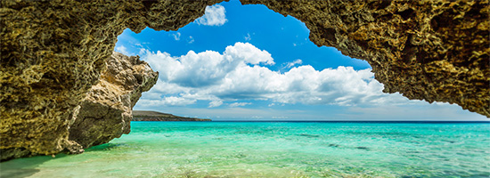 Playa Grote Knip con arena clara, agua turquesa y acantilados rocosos en Curazao.