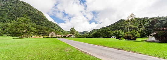 Paisaje verde con carretera, montañas cubiertas de vegetación y cielo parcialmente nublado en el Valle de Antón, Panamá.