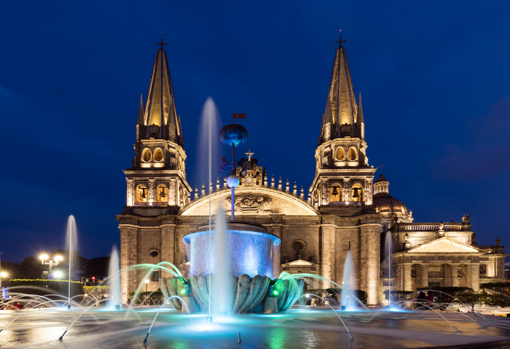 Guadalajara Cathedral and fountain illuminated at night.