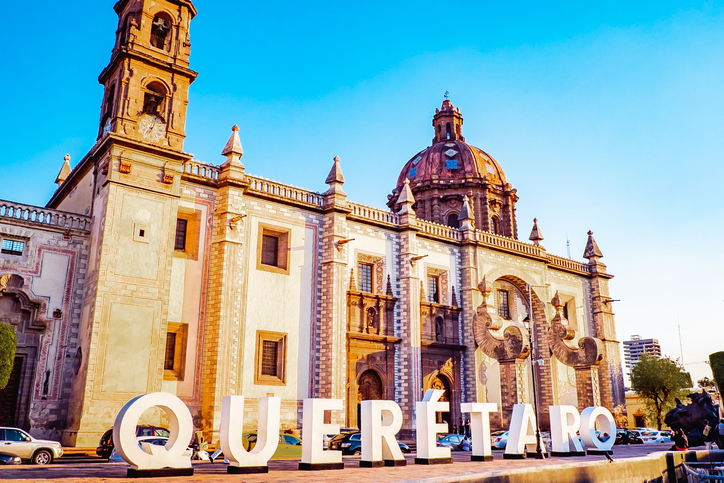Letrero de Querétaro frente a iglesia barroca en el centro histórico al atardecer.