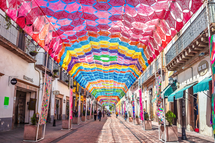 Calle peatonal en el centro de Querétaro decorada con banderillas de colores.