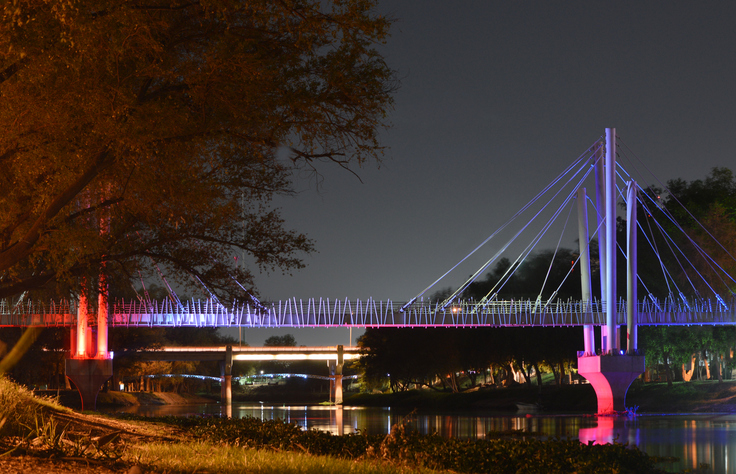 Puente que cruza el Río Tamazula, iluminado con luces de neón por la noche.