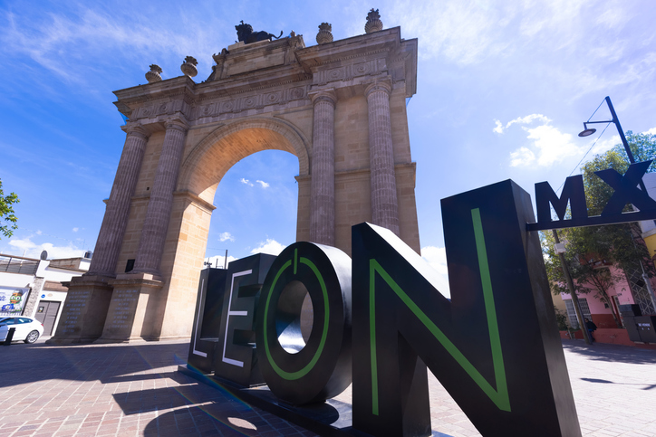 Arco de la Calzada iluminado por el sol, acompañado por las letras turísticas de León, Guanajuato.