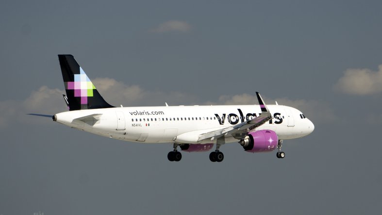 Volaris airbus initiating landing in a sky with clouds.