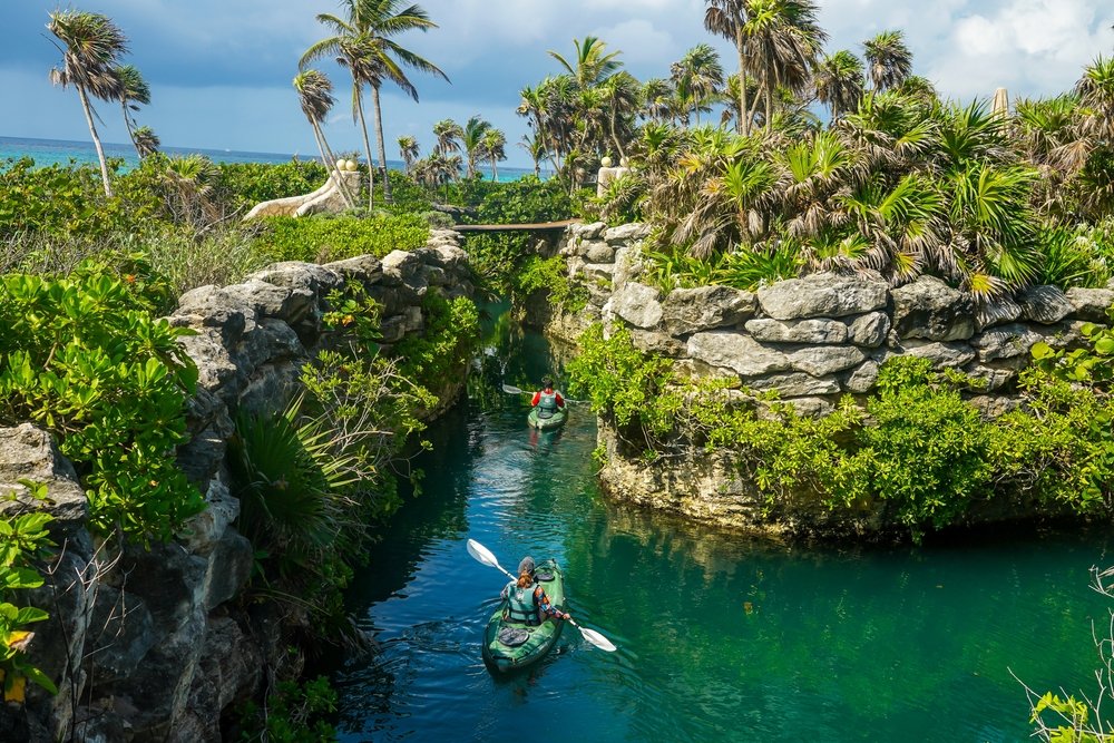 Two people kayaking across lakes in Cancun’s jungle.