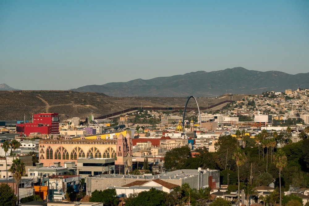 Vista aérea de la ciudad de Tijuana, con el muro fronterizo y las montañas de fondo.