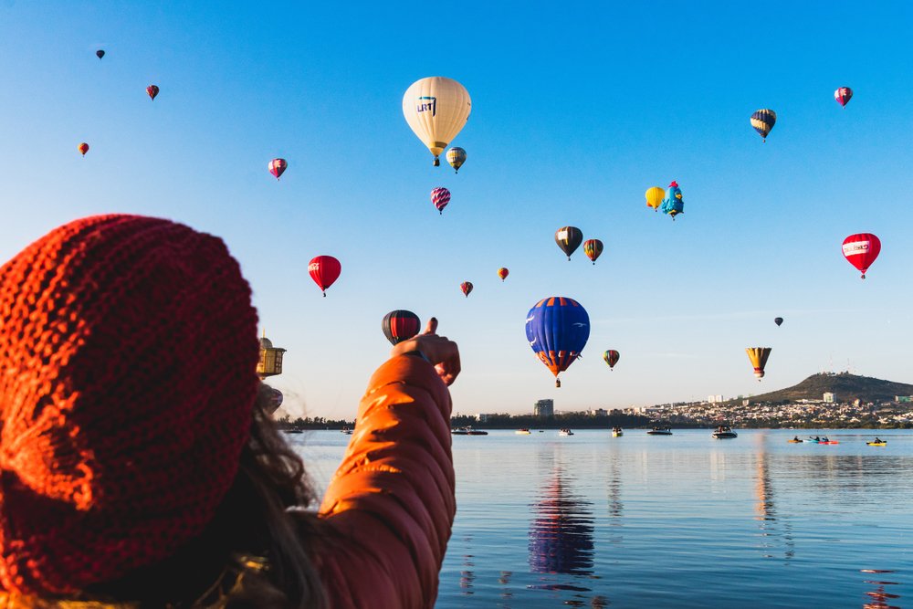 Joven turista observa los globos aerostáticos durante el Festival Internacional del Globo en León.