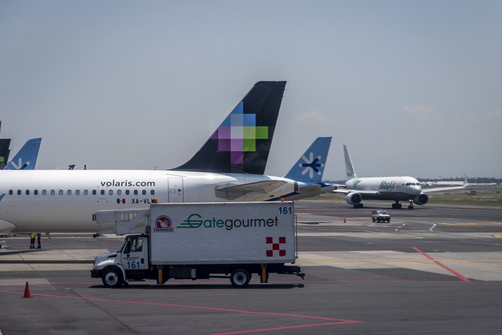 Avión de Volaris en pista de aterrizaje, con un camión de carga de equipaje enfrente.