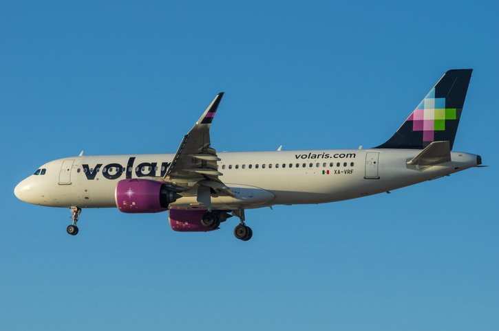 Perfil de un avión de Volaris iniciando el aterrizaje sobre un cielo despejado.