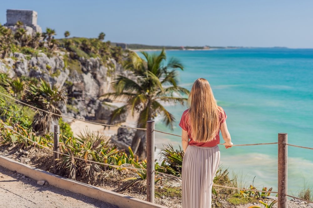 Mujer turista admirando las playas de Cancún desde una carretera en lo alto.