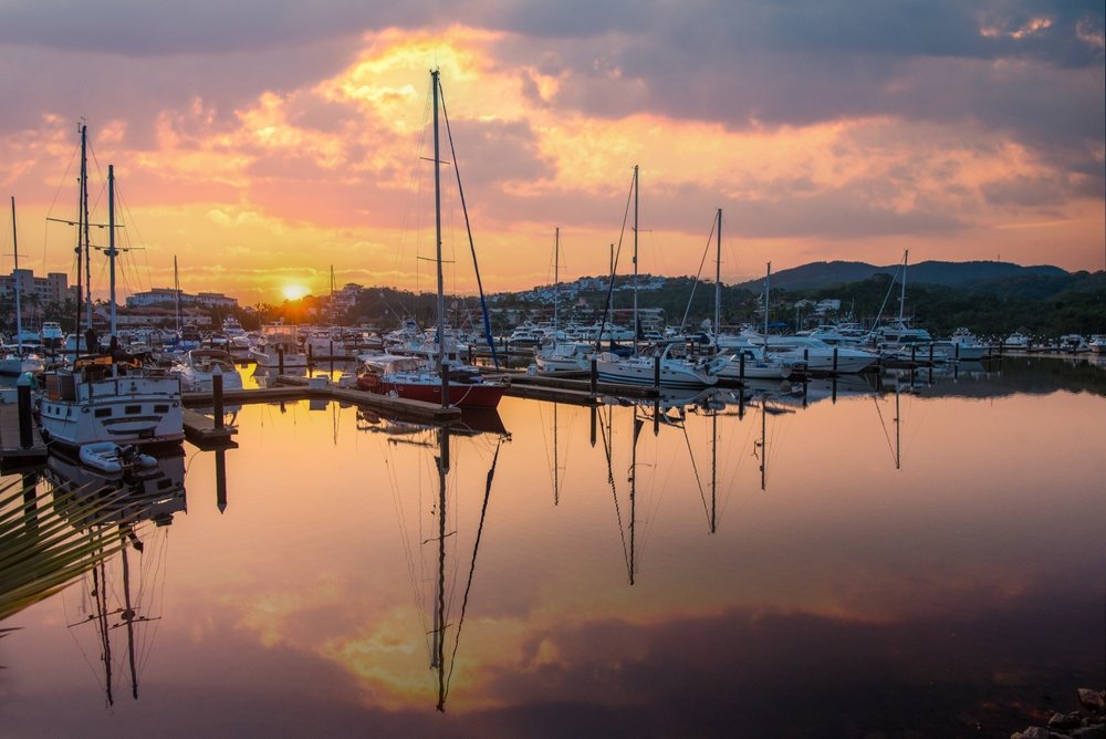Embarcaciones estacionadas en la marina de Ixtapa, con el sol del atardecer reflejado en el mar.