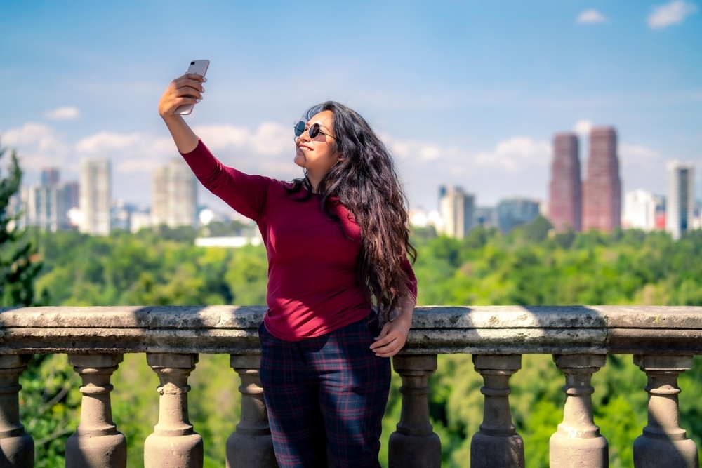 Una joven turista tomando una foto con un smartphone en el Castillo de Chapultepec en la ciudad de México.