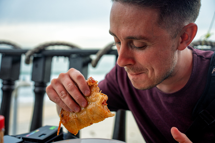 A young male eating a taco near Playas de Tijuana.