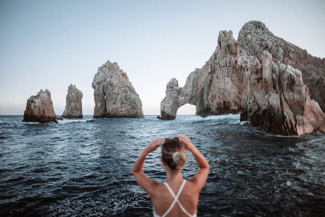 Mujer de espaldas admira el mar y el Cabo San Lucas.