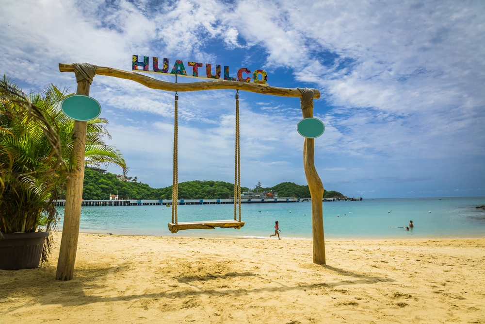 Huatulco sign above a wooden hammock in the beach in Bahías de Huatulco.