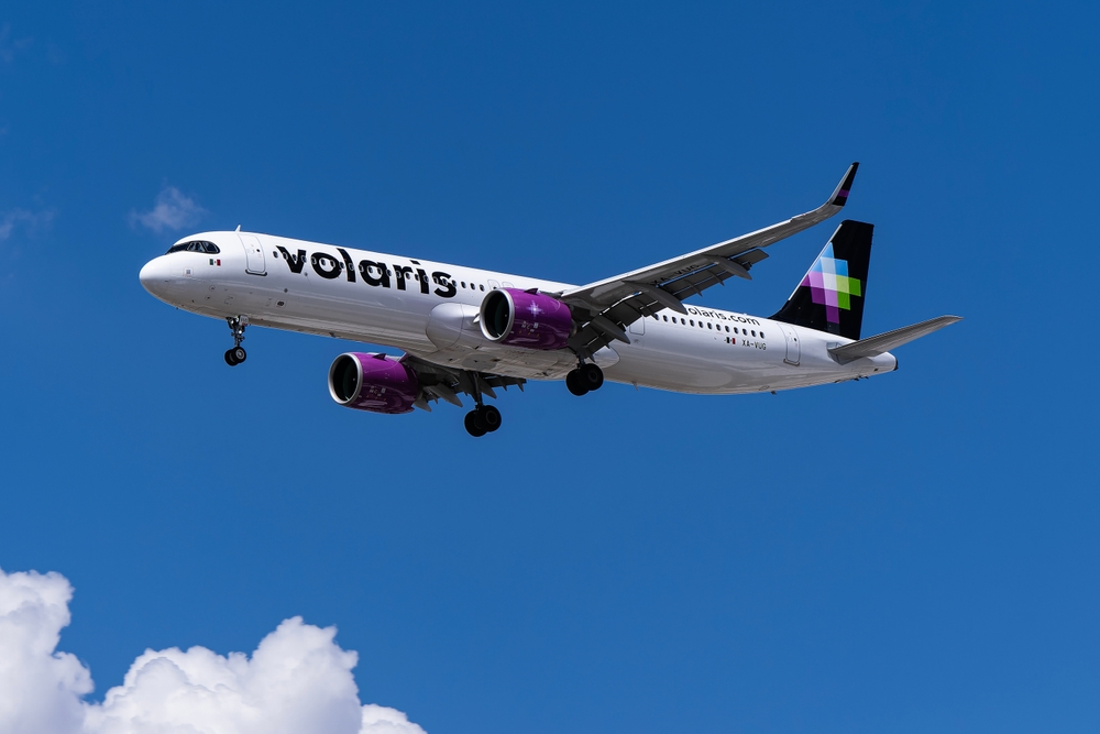 Volaris airbus flying across a blue sky.