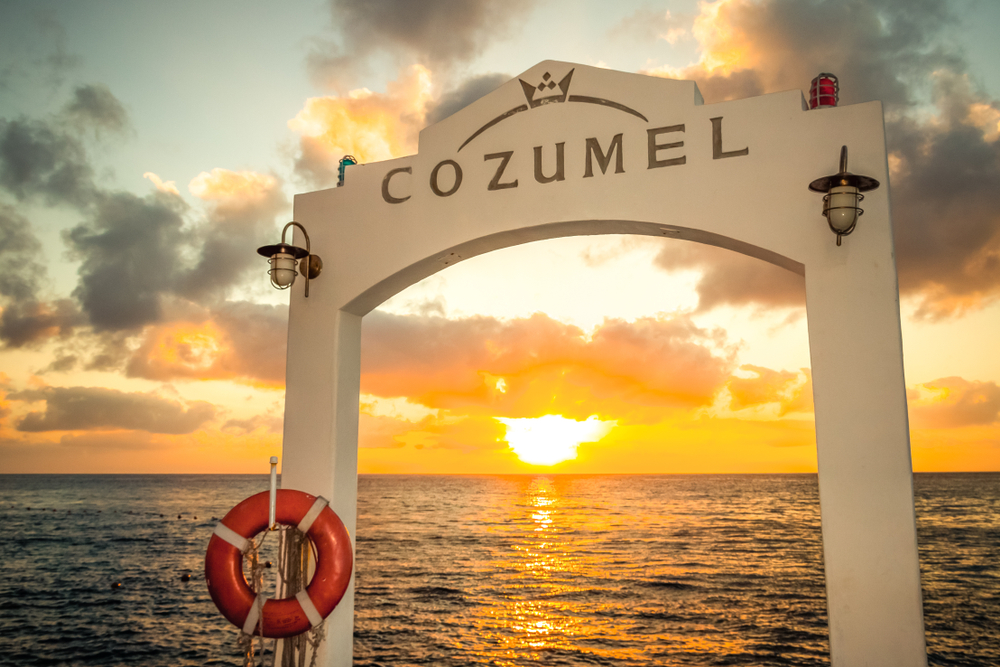 Cozumel sign in the pier, with sunset on the background.