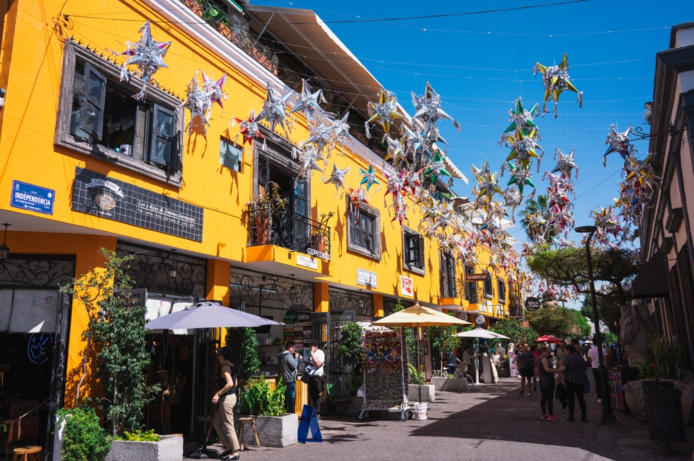 Colorida calle colonial con turistas y visitantes comprando artesanías mexicanas