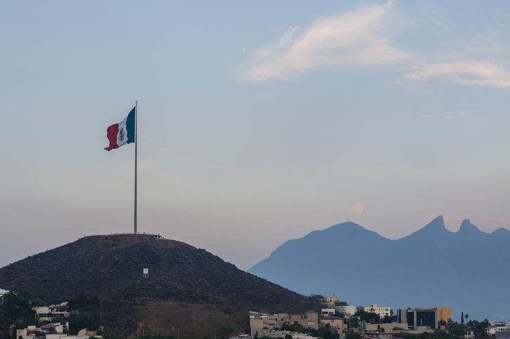 Monterrey’s mountain hills: Cerro de la Silla in the background, and a big Mexican flag in the front one.
