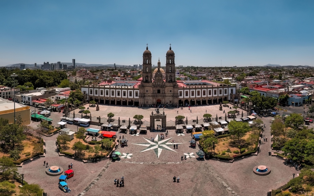 Vista panorámica de la Plaza Tlaquepaque y la iglesia en Guadalajara, México, bajo un cielo azul claro.
