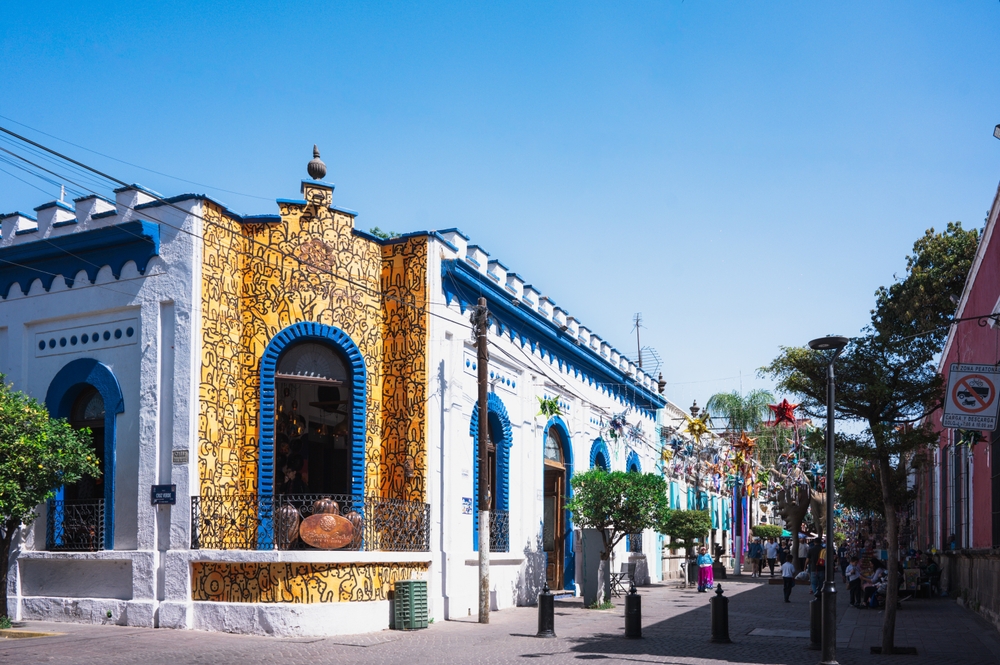 Colorida calle colonial con turistas y visitantes comprando artesanías mexicanas