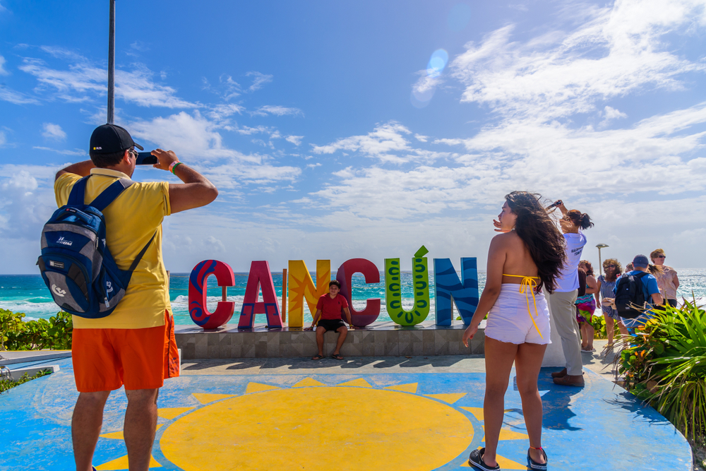 Turistas sacando fotos al cartel de Cancún